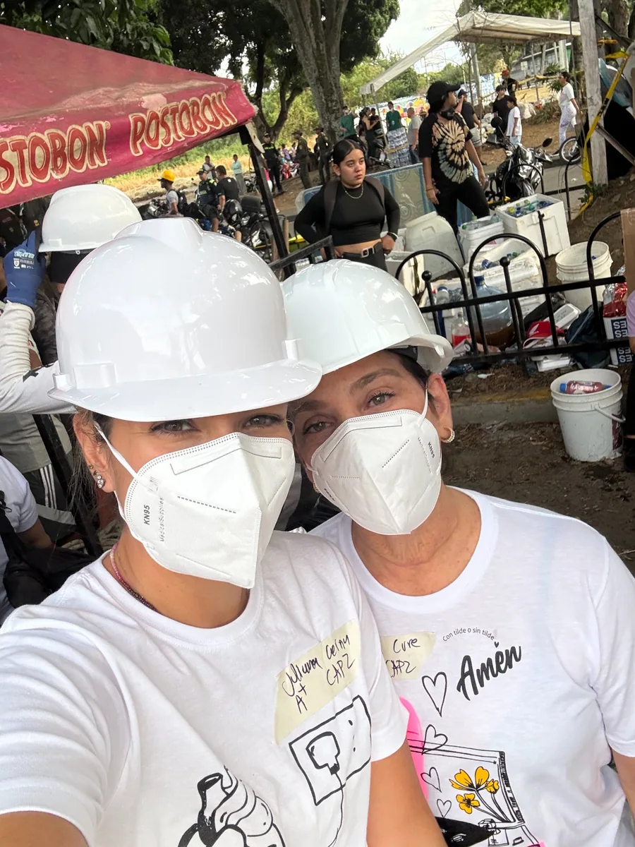 Dos personas con cascos blancos, tapabocas y camisetas de AMEN.