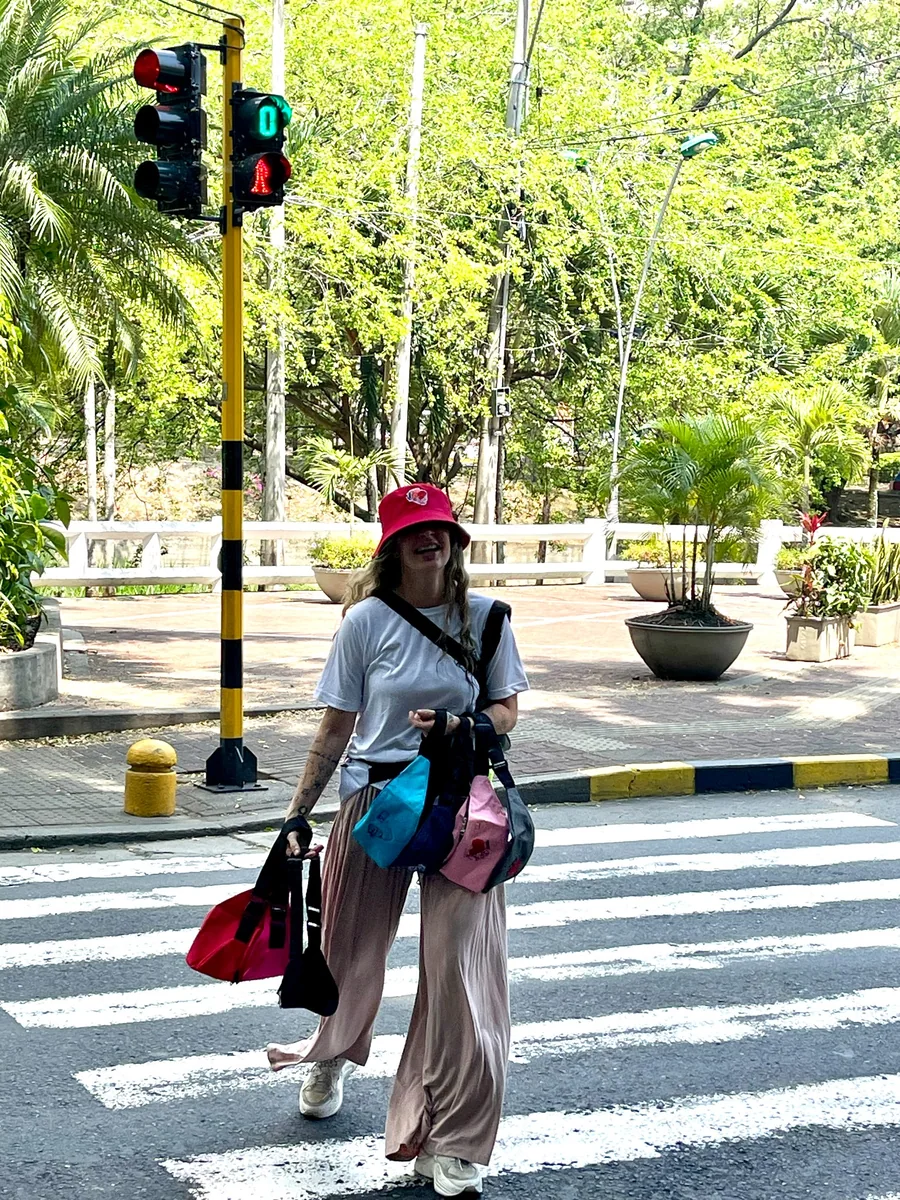 Una persona camina con canguros de colores y un sombrero con el logo de AMEN.